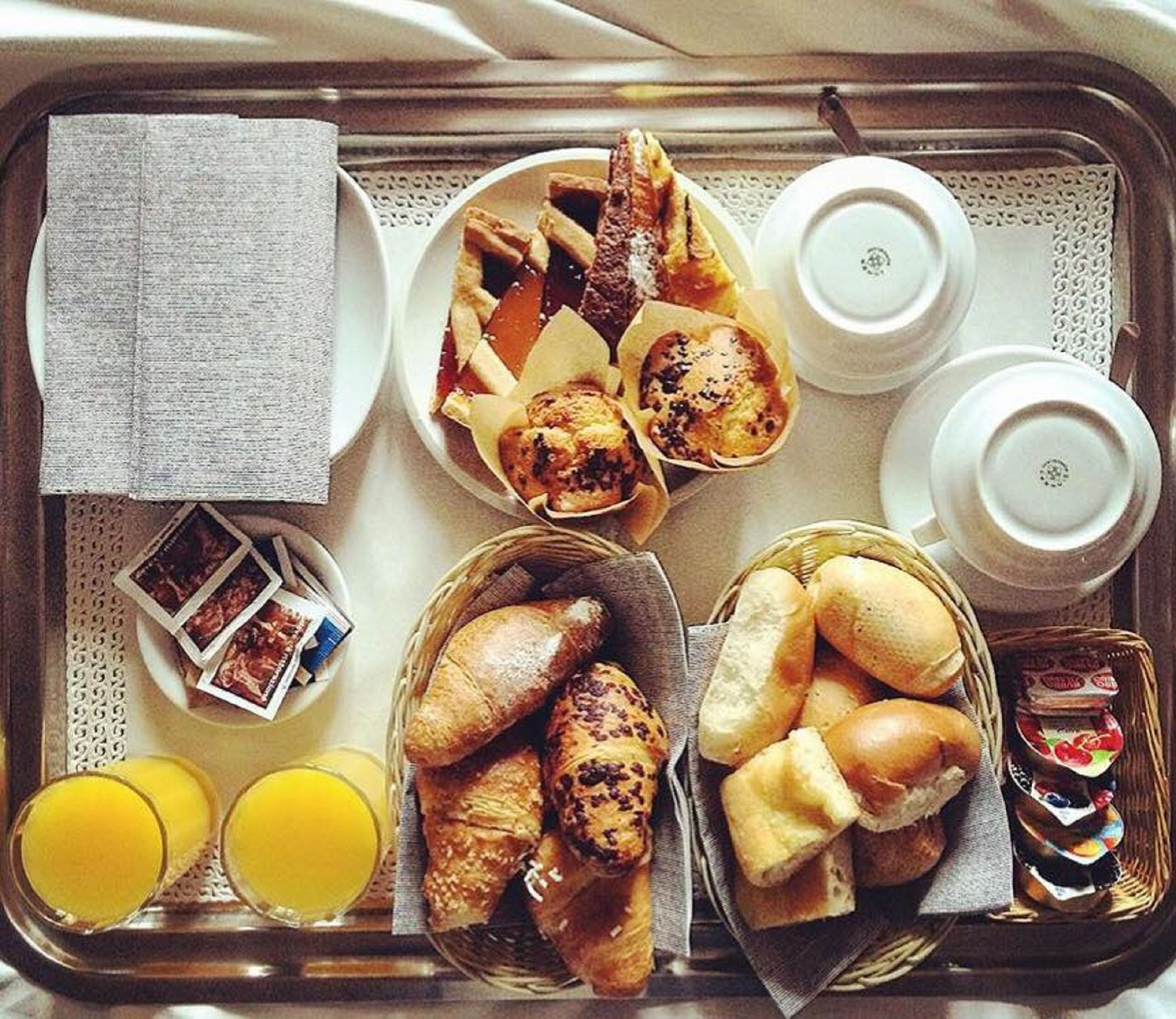A tray with breakfast items including pastries, bread, and juice.