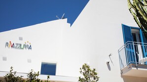 A building with a white facade, a blue window, and a sign reading "RIMAZZURA".