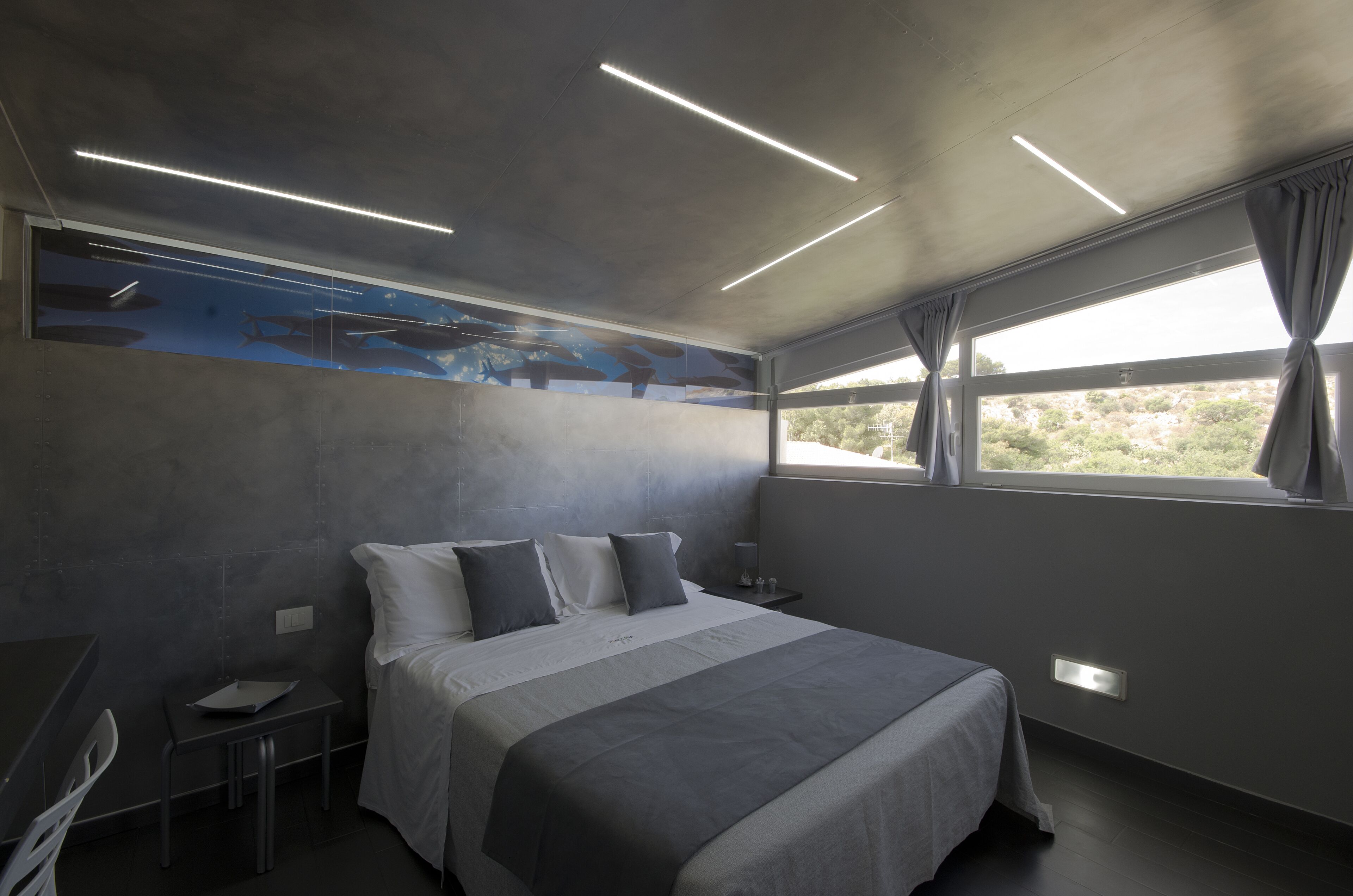 A modern bedroom with a large bed, a desk, and a window with curtains.
