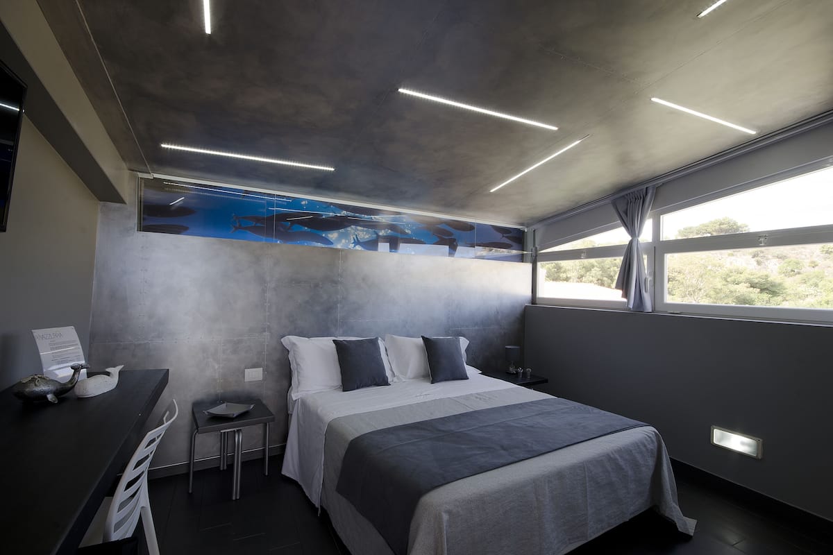 Une chambre d’hôtel moderne, équipée d’un lit, d’un bureau et offrant une vue sur l’extérieur.