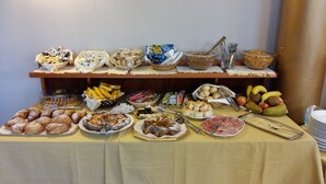 Una mesa de buffet con diversos alimentos, incluyendo pasteles, frutas y salsas.