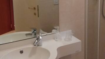 Un baño con lavamanos, espejo, ducha e inodoro.