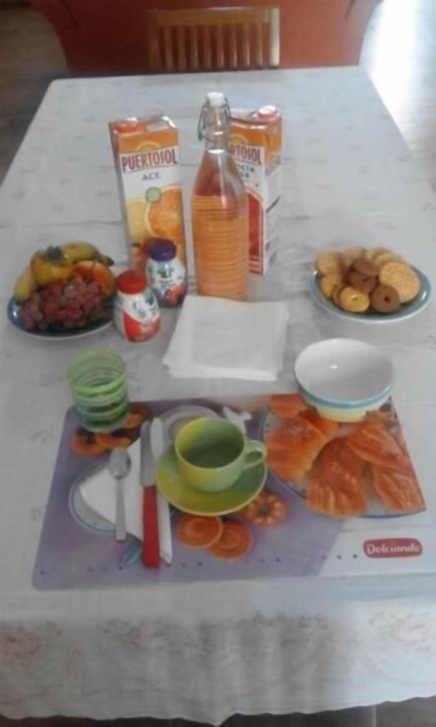 A dining table with a placemat, plates, bowls, a bottle, and various food items.