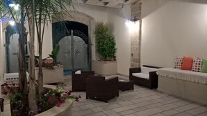 Un espacio al aire libre acogedor con mobiliario de mimbre, una planta en maceta y un muro decorativo.