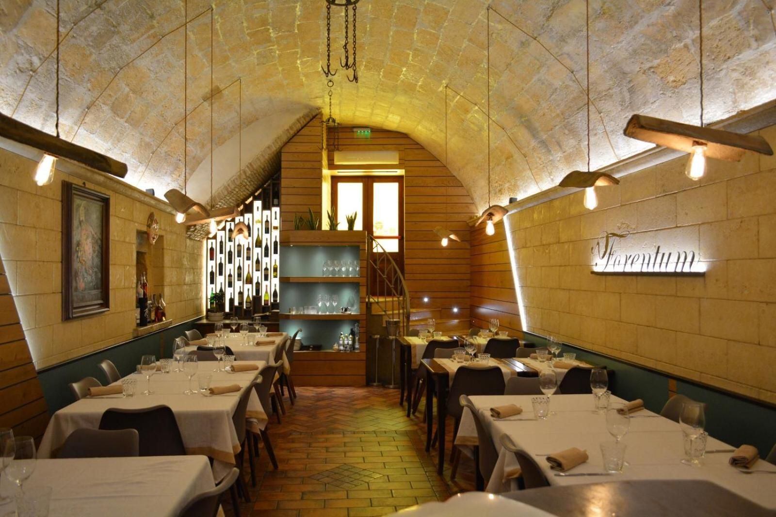 An interior with tables set for dining, a staircase, and a sign reading 'Forentum'.