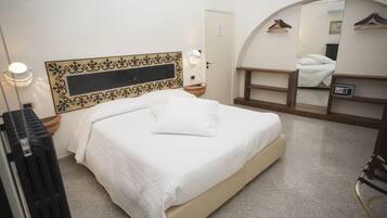 Une chambre d’hôtel bien rangée, avec un lit, un miroir, un radiateur et une armoire.