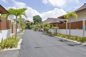 A residential street with houses, palm trees, and a clear sky. - CAPITAL O887 Orchid Garden Villa 2 (Rawai)