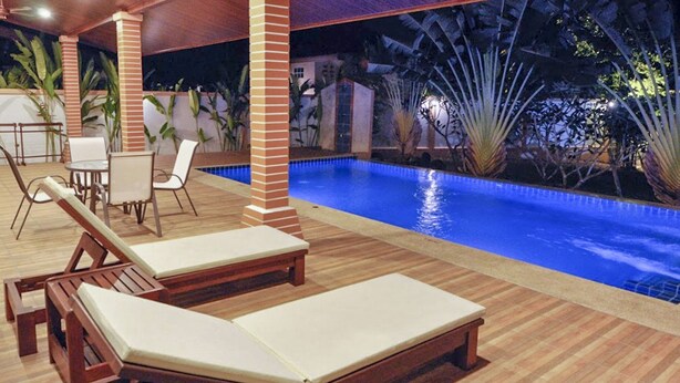 A poolside area with wooden loungers and a pool. - CAPITAL O887 Orchid Garden Villa 2 (Rawai)