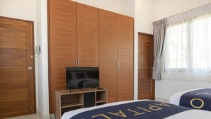A hotel room with wooden wardrobes, a TV on a wooden stand, and two beds with matching headboards. - CAPITAL O887 Orchid Garden Villa 2 (Rawai)