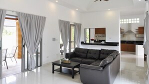 A modern living room with a sectional sofa, a coffee table, and a ceiling fan. - CAPITAL O887 Orchid Garden Villa 2 (Rawai)