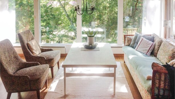 A cozy living room with a white coffee table, two armchairs, and a sofa. A chandelier hangs above the table, and a potted plant is on the table. - 2 bedroom amazing home in Yngsjö (Yngsjö)