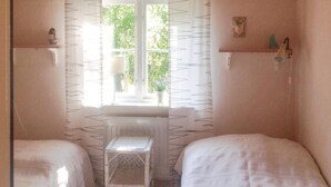 A small, cozy room with two single beds, a radiator, a window with a view of greenery, and a shelf with a small plant. - 2 bedroom amazing home in Yngsjö (Yngsjö)