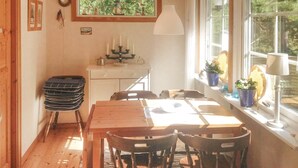 A dining area with a wooden table and chairs, a white lamp, and a window with plants. - 2 bedroom amazing home in Yngsjö (Yngsjö)