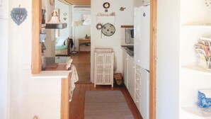 A narrow kitchen with wooden cabinets, a sink, and a small refrigerator. There is a window on the left and a door leading to another room. - 2 bedroom amazing home in Yngsjö (Yngsjö)
