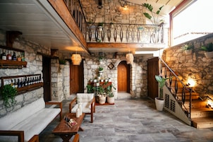 Un interior espacioso y rústico con paredes de piedra, muebles de madera y una variedad de plantas en macetas.