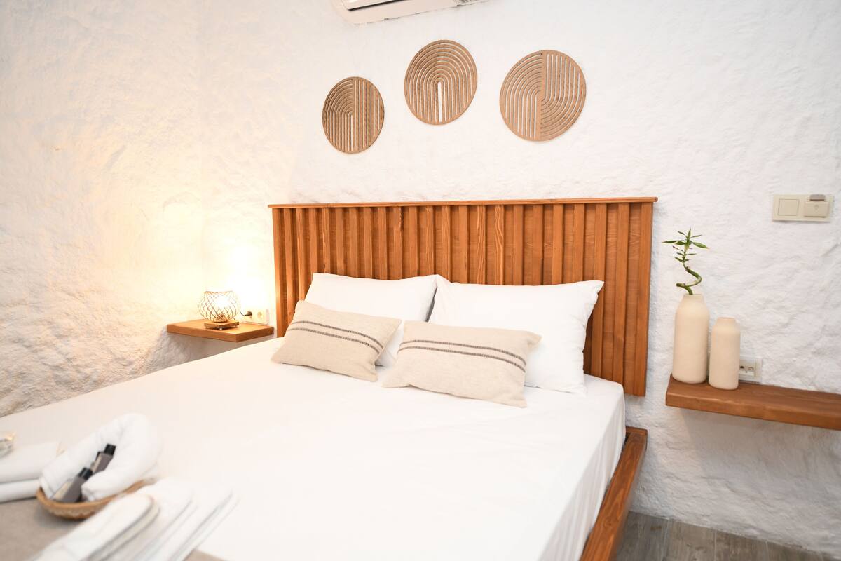 A neatly made bed with a wooden headboard, white bedding, and two bedside tables with decorative items.