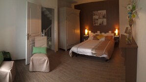 A bedroom with a bed, a chair, a small table, and a staircase. - Authentic mill with feet in water (near the sea) (Le Vieux-Marché)