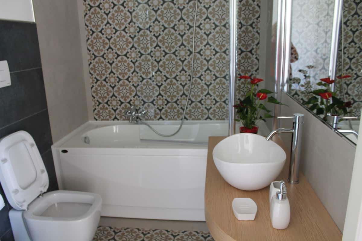 Ein modernes Badezimmer mit einer weißen Badewanne, einem weißen Waschbecken und einer Toilette.
