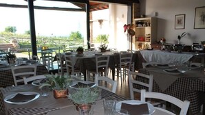 A restaurant with outdoor seating, tables set with plates, glasses, and napkins, and a view of the outdoors. - Country House Erba Regina (Frascati)