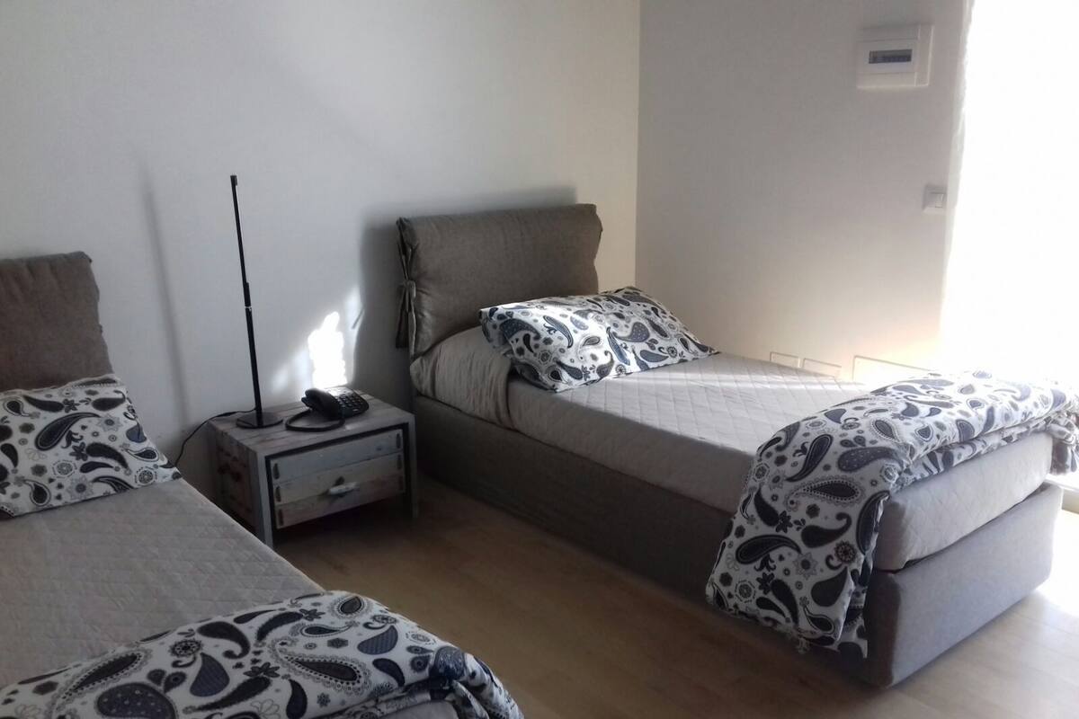 Ein Schlafzimmer mit zwei Einzelbetten, einem Nachttisch mit Lampe und einem Beistelltisch mit Telefon.