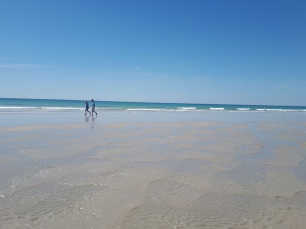 A beach with a wide expanse of sand and gentle waves.