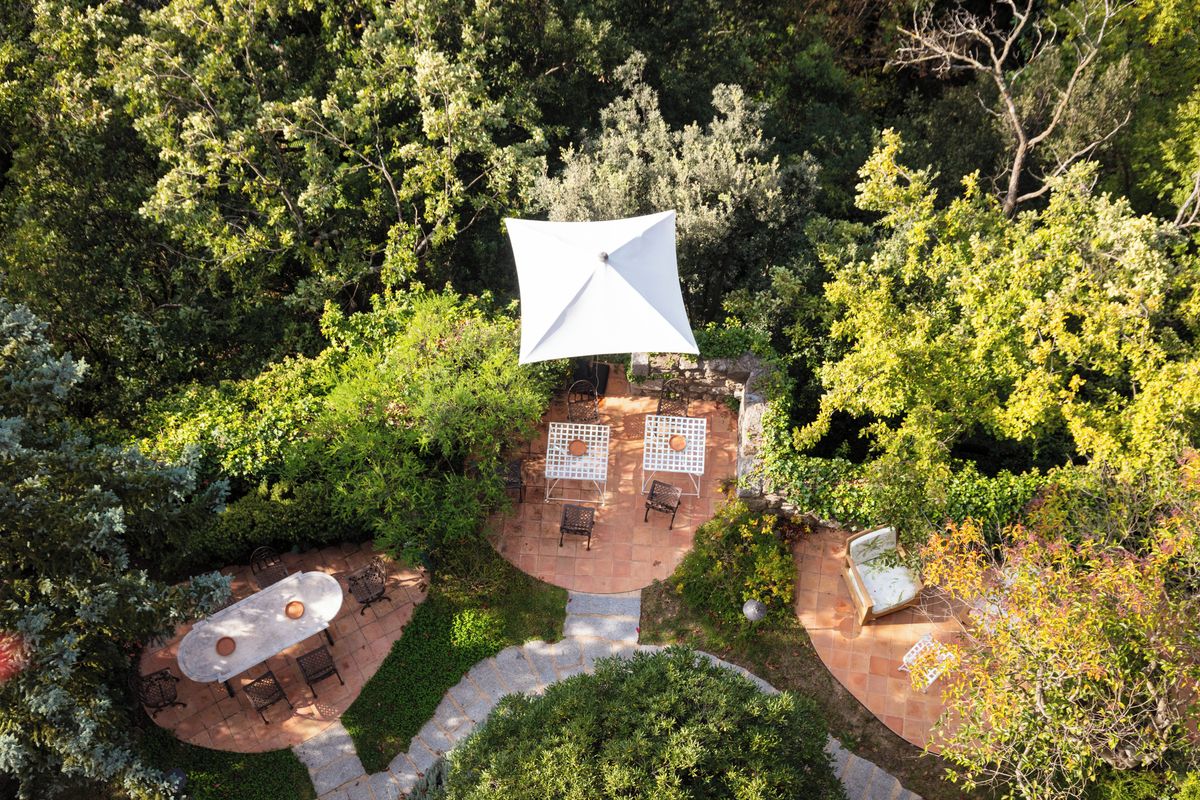 An outdoor patio area with a central umbrella, surrounded by seating and a stone pathway.