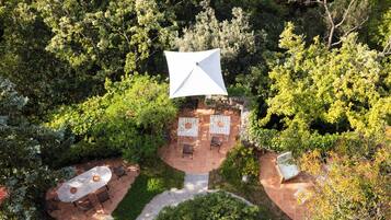 An outdoor patio area with a central umbrella, surrounded by seating and a stone pathway.