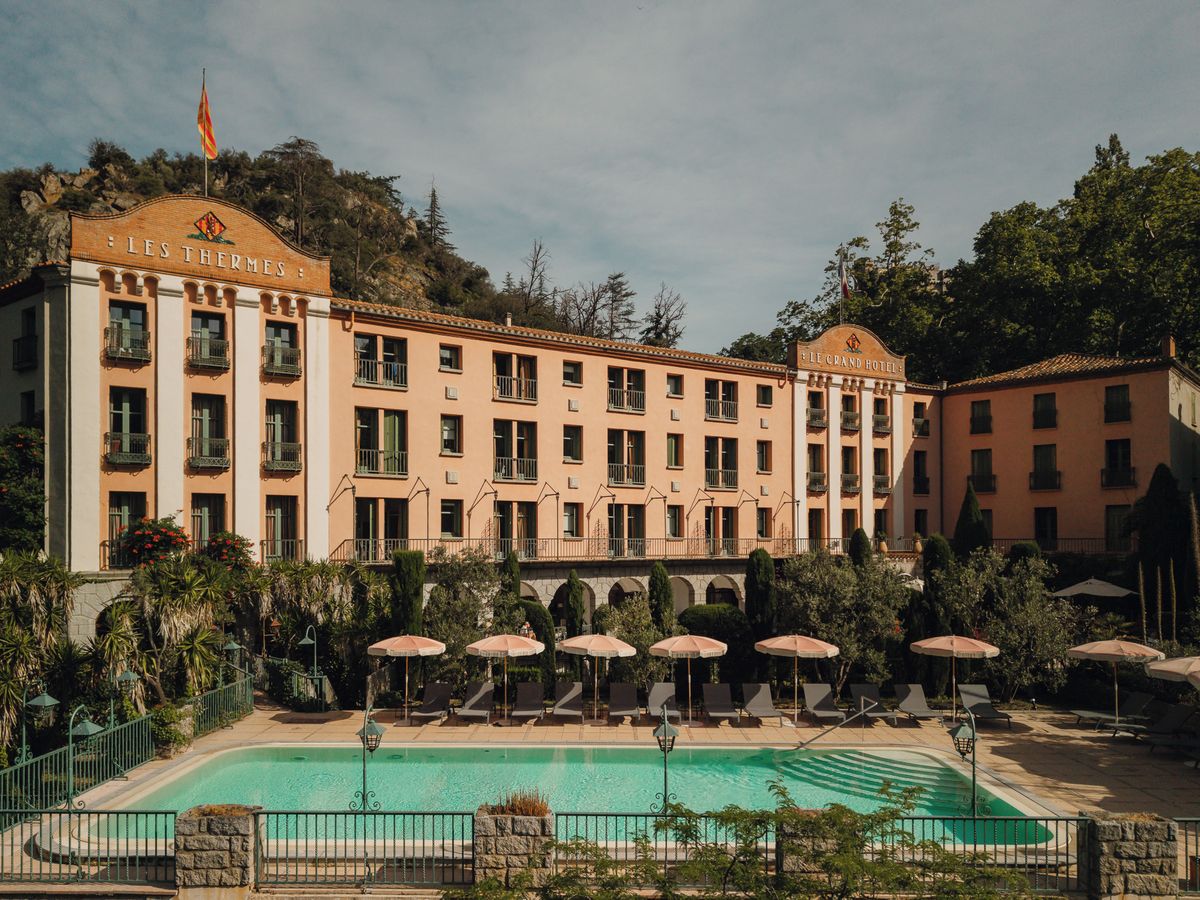 Ein Hotel mit Pool, Außenbereich und einer Bergkulisse.