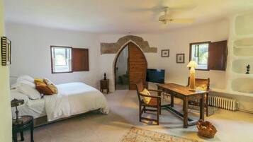 A bedroom with a bed, a desk, a chair, a lamp, a radiator, and a window.
