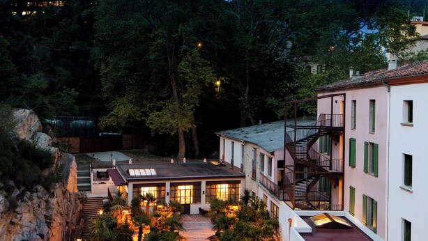 Un hotel moderno con varios niveles, terrazas exteriores y un patio central.