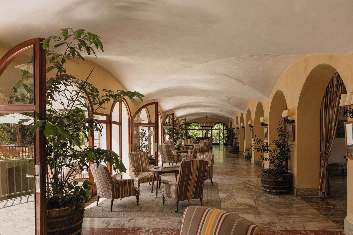A spacious lobby with arched ceilings, striped chairs, and potted plants.