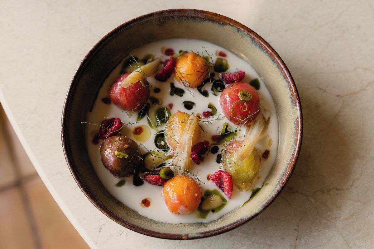 A bowl of soup with various vegetables and herbs.