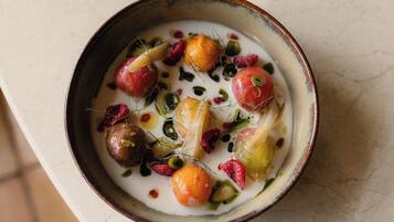 A bowl of soup with various vegetables and herbs.