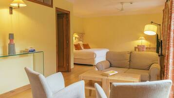 Ein Hotelzimmer mit Bett, Sofa, Glastisch und Schreibtisch mit Lampe.