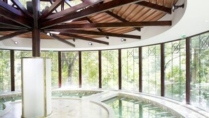 Una piscina circular cubierta con techo de madera y ventanas amplias.