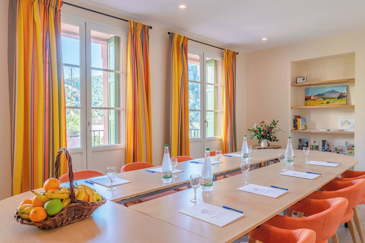 Una sala de conferencias con una mesa larga, sillas y una cesta de fruta.