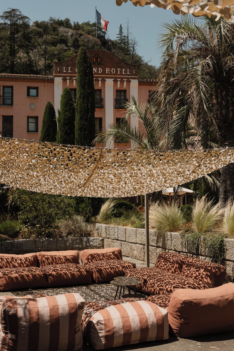 Un hôtel doté d’une terrasse avec des sièges en plein air et un auvent décoratif.