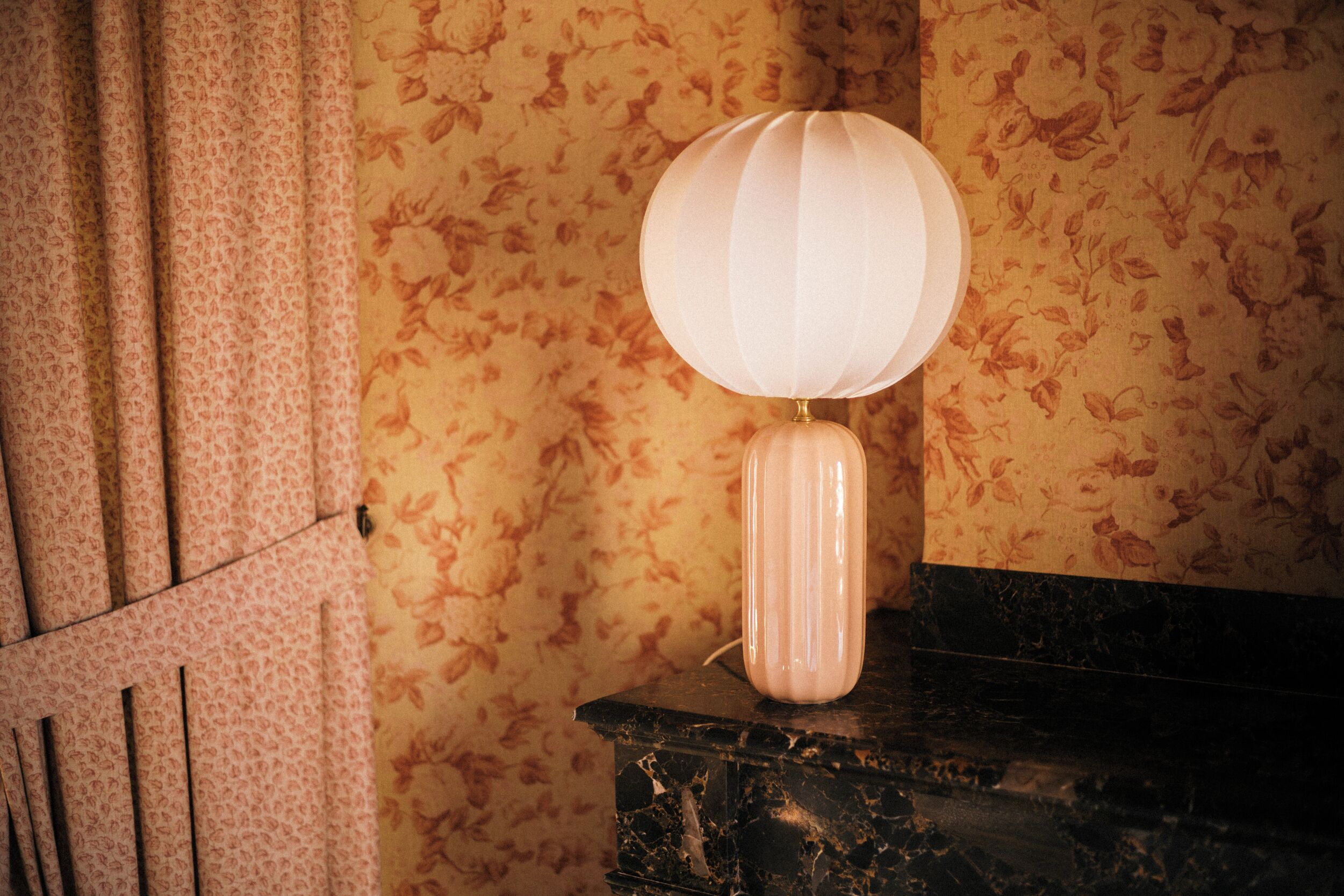 A lamp with a spherical shade on a marble surface.