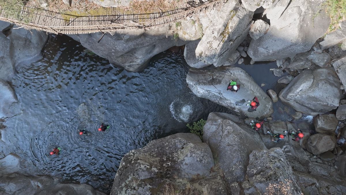 Een rotsachtig landschap met een brug en een waterpartij.