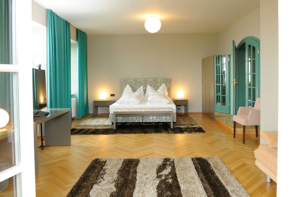 A modern bedroom with a large bed, bedside tables, a desk, and a chair.