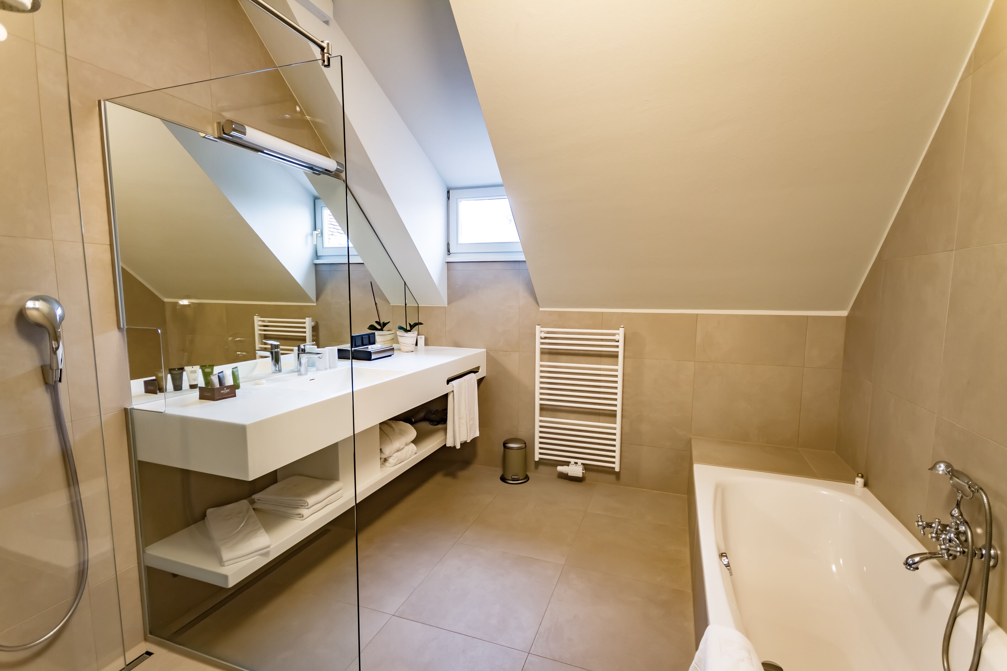 Un baño moderno con un espejo grande, una bañera y una ducha.