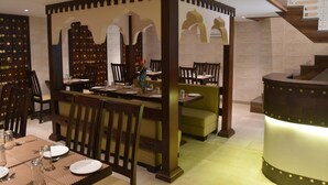 Un comedor con techo alto, una escalera y un separador decorativo.