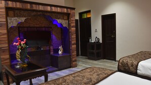 Habitación de hotel con televisor, una mesita con un florero, cama y puerta.