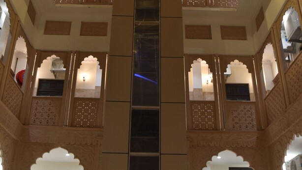 Un atrio de varios niveles con arcos decorativos y una escalera central.