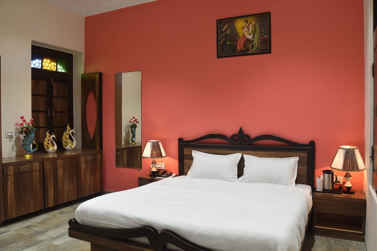 Quarto de hotel com uma cama, mesas de cabeceira, um espelho, uma porta com vitrais e um quadro na parede.