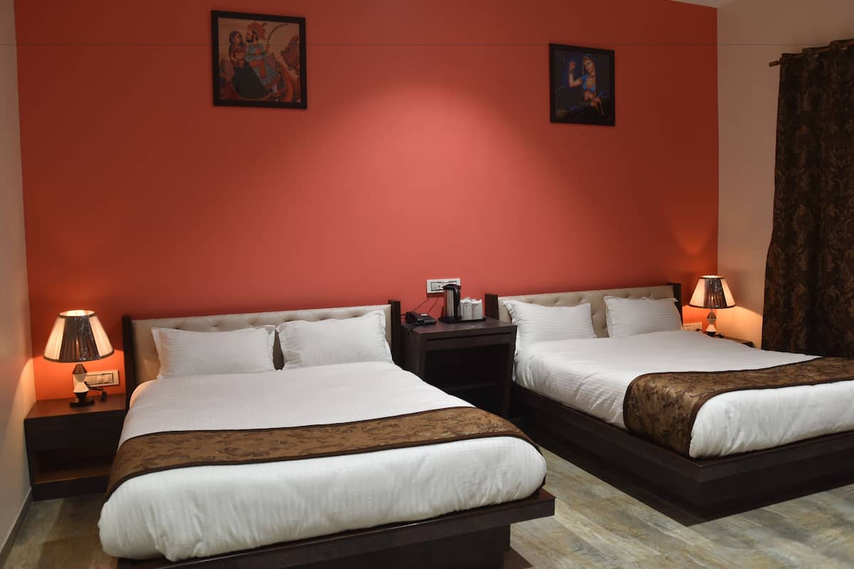 Quarto de hotel com duas camas, uma parede vermelha e um tapete marrom.