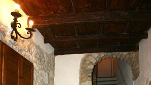 A stone-walled room with a staircase leading to a wooden door. - Residenza Cardinale (Tropea)