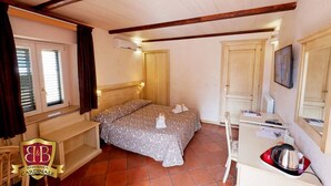 A bedroom with a bed, a desk, a chair, a wardrobe, and a window with curtains. - Residenza Cardinale (Tropea)