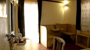 A cozy room with a wooden bench, a small table with a vase of flowers, and a wall-mounted light fixture. - Residenza Cardinale (Tropea)