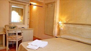 A hotel room with a bed, a desk, a chair, a wardrobe, and a mirror. - Residenza Cardinale (Tropea)